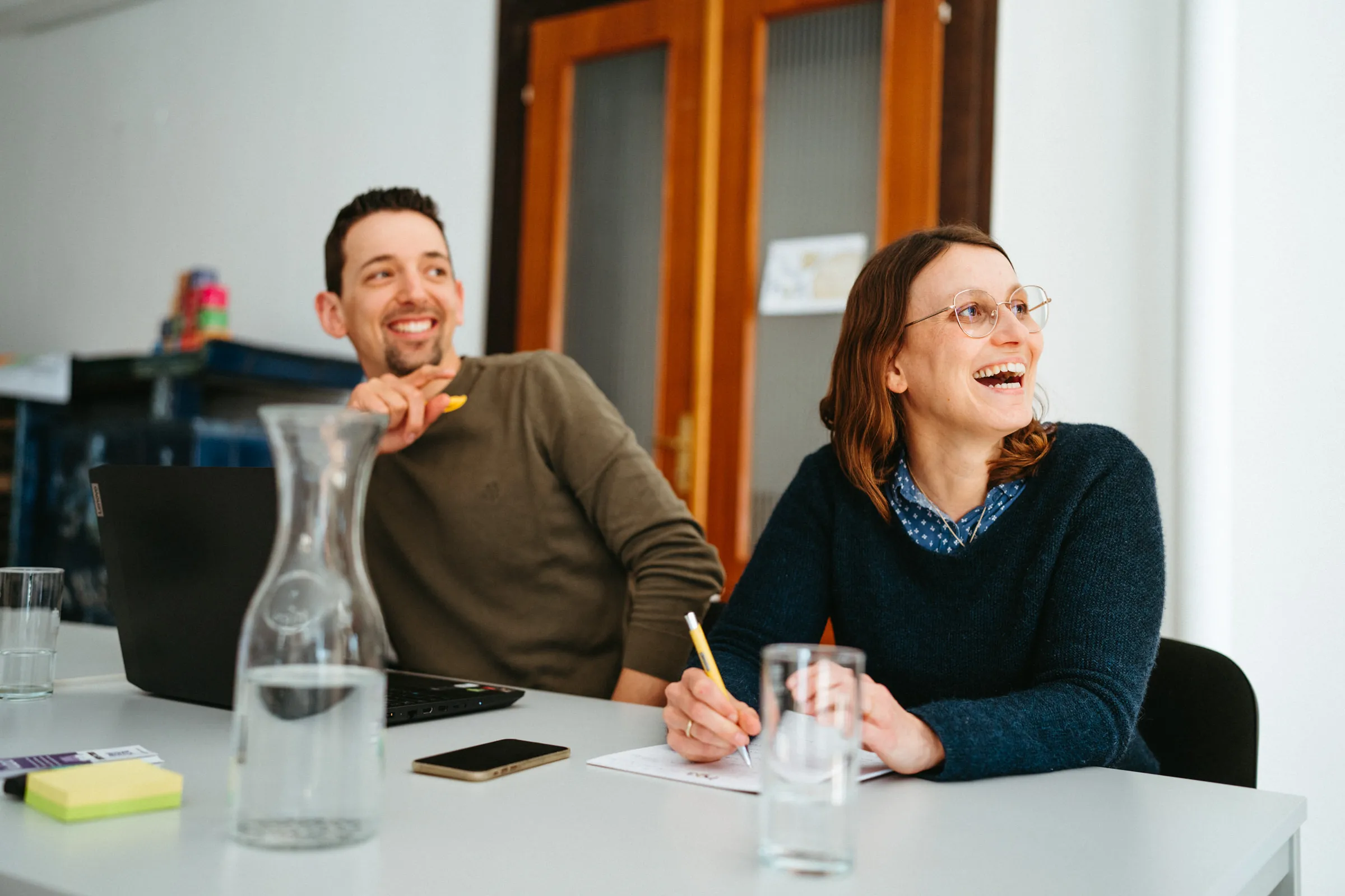 Lachende Teilnehmerinnen und Teilnehmer in einem Workshop von itell.solutions